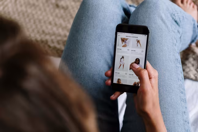 Frau mit Smartphone in der Hand besucht einen Onlineshop
